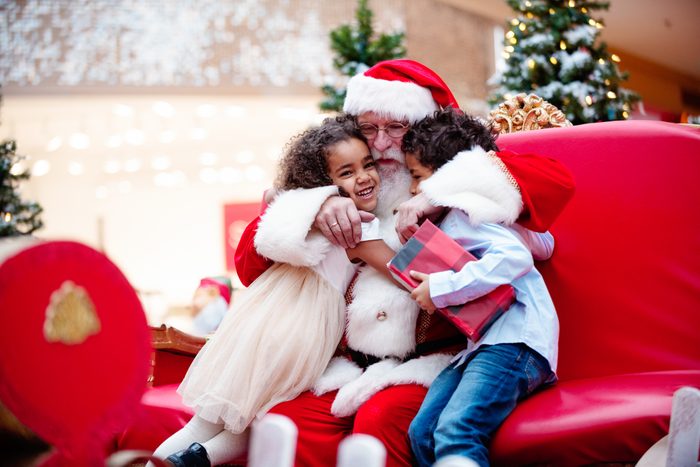 two young girls hugging santa at the mall