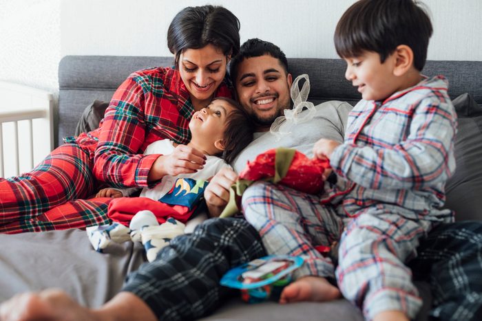 family in christmas pajamas snuggling on the couch at home