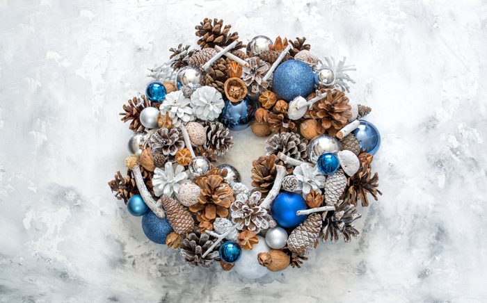 Homemade Christmas wreath in trendy colors - Classic Blue and White on a white concrete background. The concept of the new year, merry christmas, winter holidays.