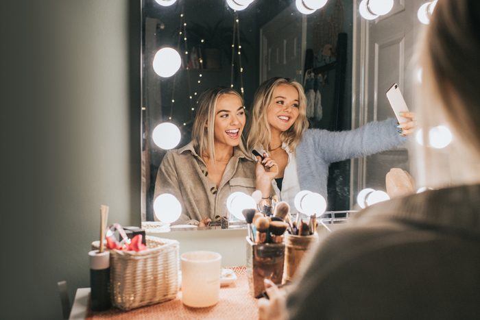 Young happy woman take a selfie as they look into a mirror and apply make-up