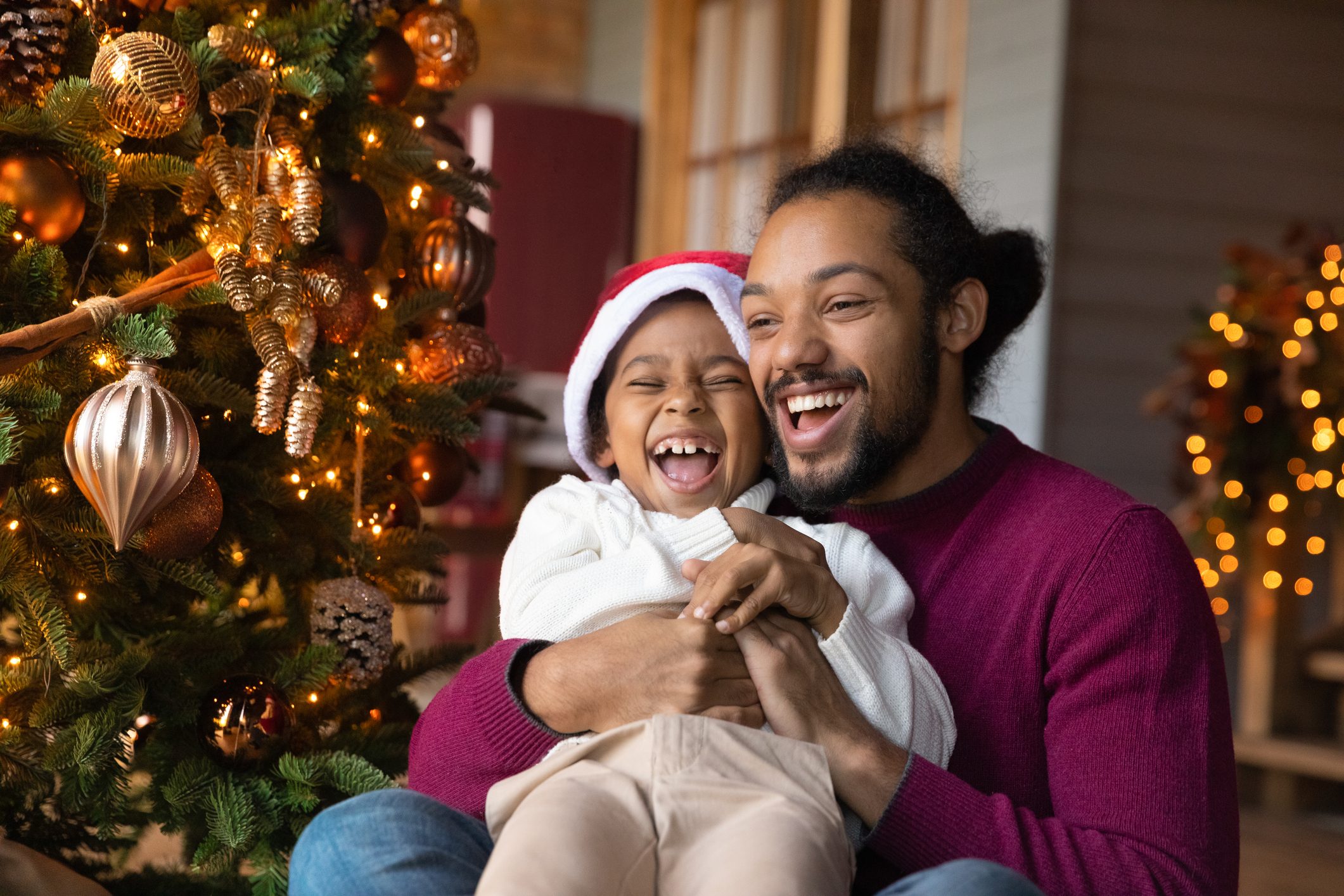 Excited biracial father and son play near fir tree