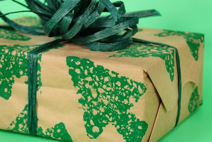 Christmas gift wrapped with green hand stamped repurposed brown paper bag and recycled paper ribbon with green background