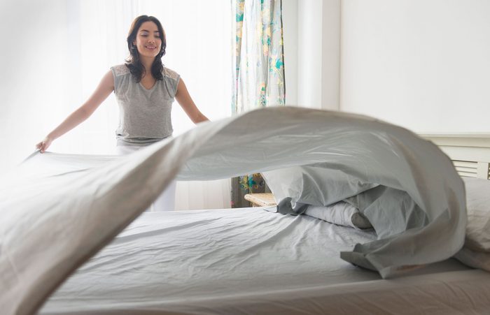 woman making her bed with clean sheets