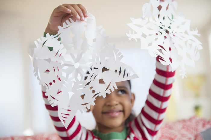 Mixed race girl holding paper snowflakes