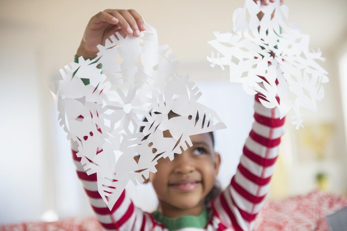 young girl holding paper snowflakes