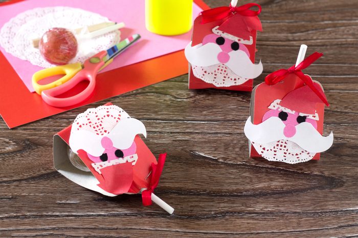 The child create a greeting packaging for candy Santa Claus on paper