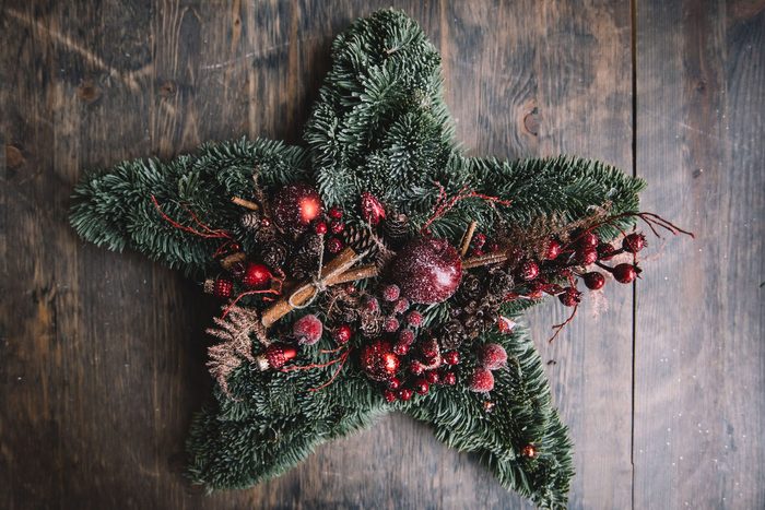 Beautiful festive winter hand made wreath on the rustic wooden table background, top view