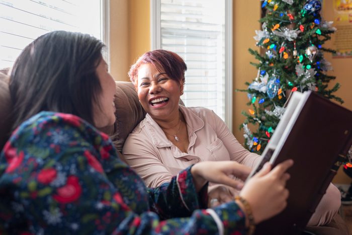 Mother and daughter looking at photo album near Christmas tree