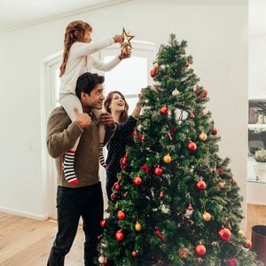 family decorating a christmas tree and placing the star at the top