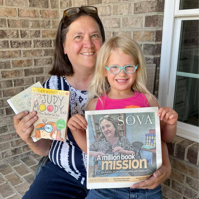 Jennifer Williams holding to books with her daughter sitting on her lap holding a newspaper celebrating William's mission