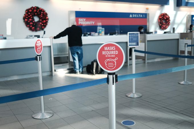 man standing at the Delta counter in an airport decorated for christmas and the holiday season