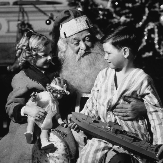 a young boy and girl on santa's knee at christmas time