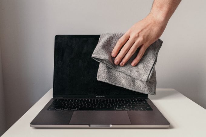 wiping laptop screen with dry microfiber cloth