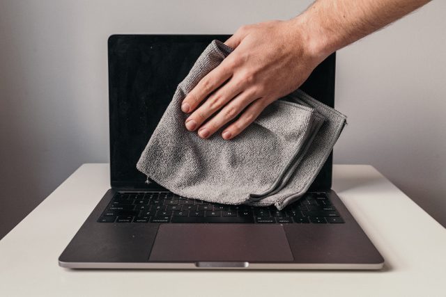 wiping the center of the laptop screen with microfiber cloth