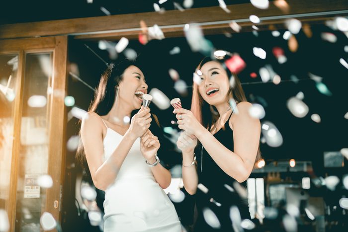 two young women using confetti poppers at new year's party