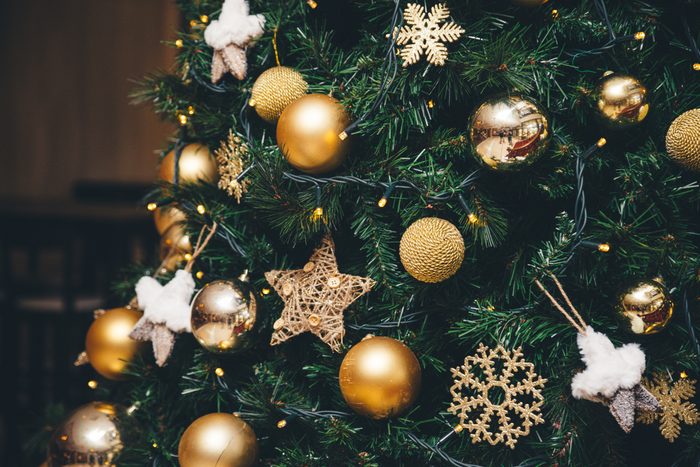 Background of fluffy branches green color New Year trees decorated with beautiful golden shiny sphere balls, toys and ornates