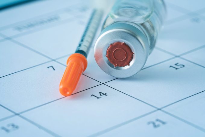 Syringe and Vaccine on top of a Calendar