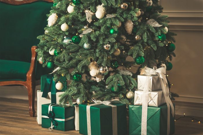 Close-Up Of Green Christmas Tree And Green Gift Box On Floor At Home