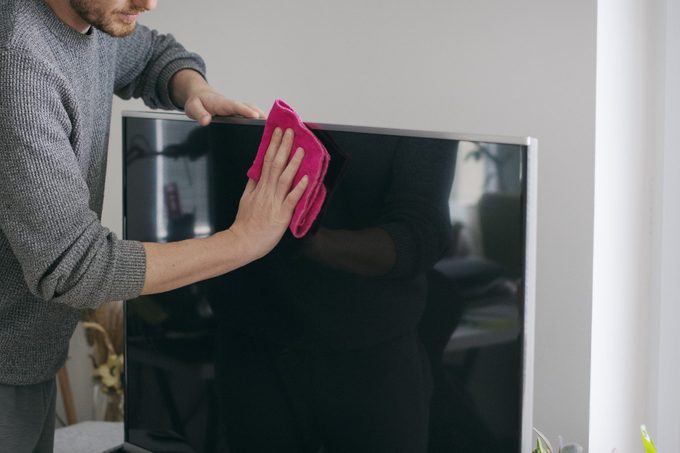 Close up of man cleaning TV screen with microfiber cloth