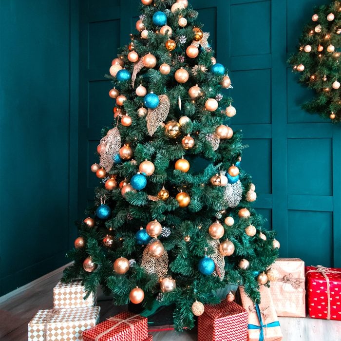 Interior of a beautiful cyan room decorated for Christmas, a lot of gift boxes and presents under a blue fir tree, festive mood atmosphere and concept of New Year