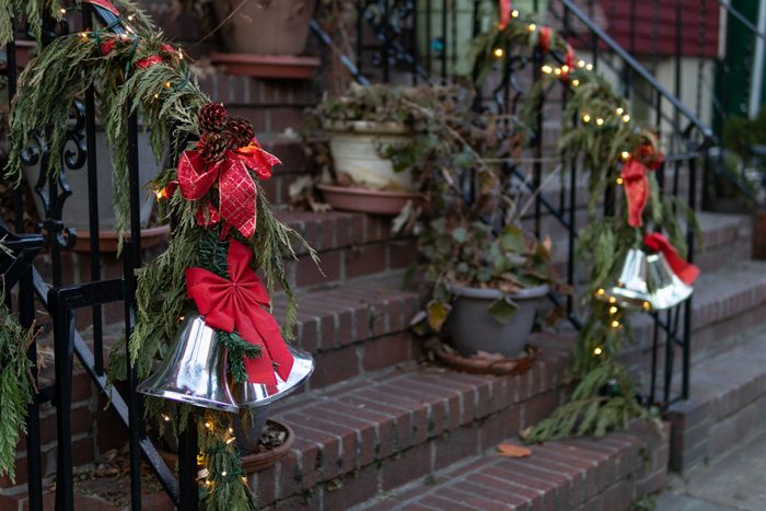Christmas decorations on an outdoor home stair railing with pine branches red bows and bells in New York City