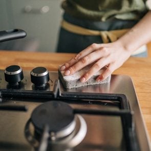 close up of person cleaning a stainless steel stove in kitchen