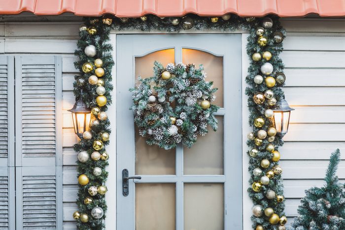 Winter rustic entrance door decorated for New year and Christmas with ornaments and Christmas lights.