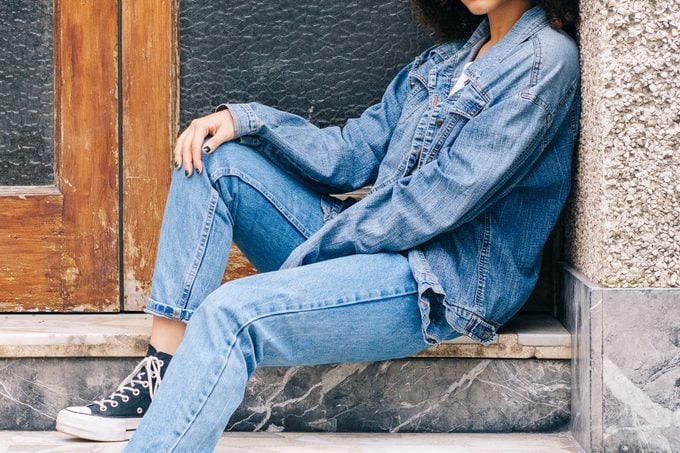 woman wearing an all denim outfit sitting on steps outside