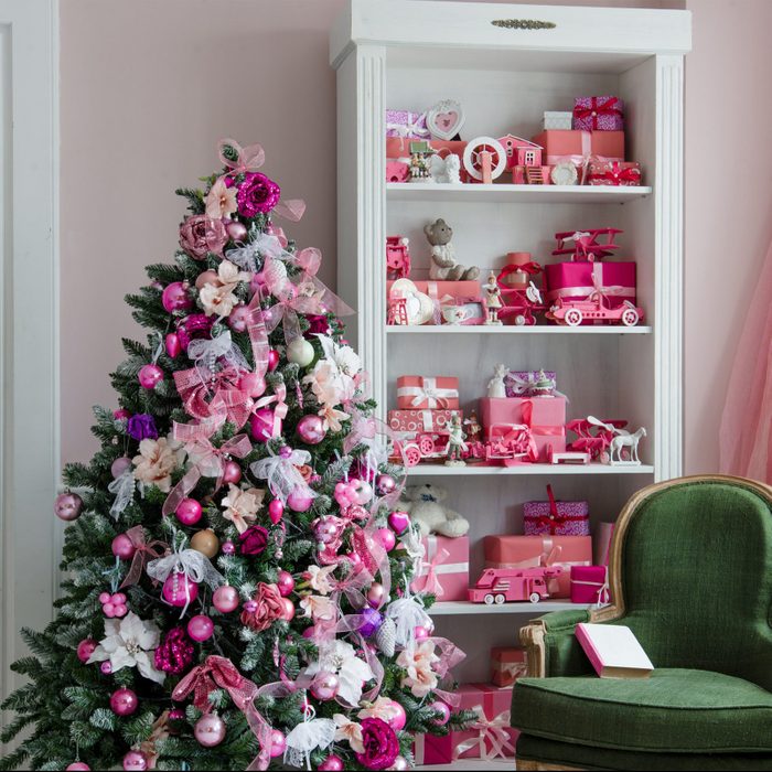 Beautiful holdiay decorated rooms with Christmas trees, shelf and pink blue gifts on it, green chair home interior
