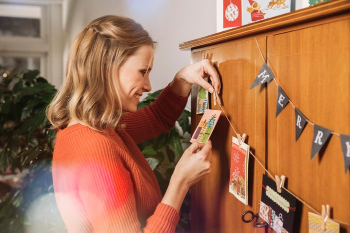Woman hanging up Holiday cards for decoration