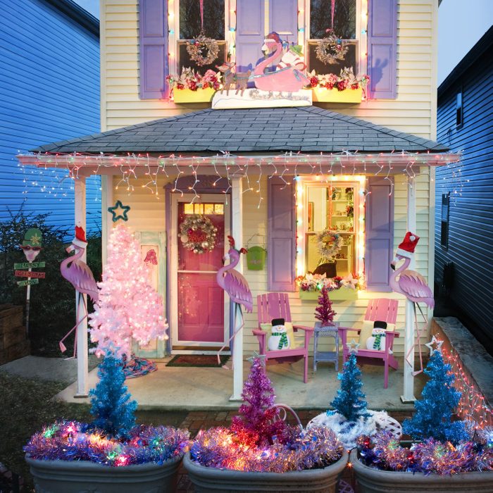 house decorated for christmas with festive flamingos in santa hats decor and colorful trees and lights