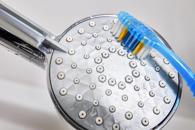 cleaning shower head with a toothbrush