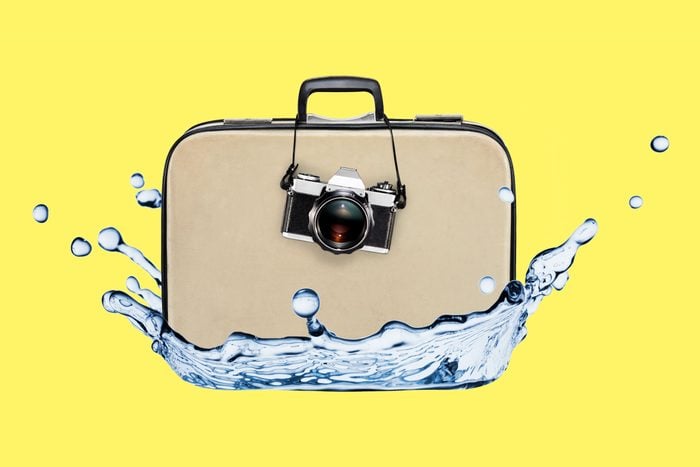 suitcase with a camera hanging on it collaged with a spash of water