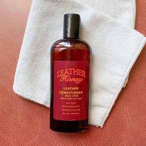 Leather Honey leather cleaner and folded gray mircofiber cleaning cloth on reddish-brown leather texture background