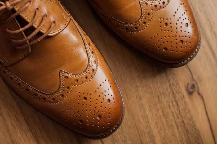 A pair of brown leather derby shoes on wood floor