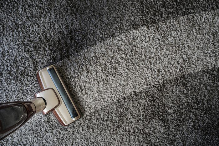 High Angle View Of Vacuum Cleaner Cleaning Carpet At Home