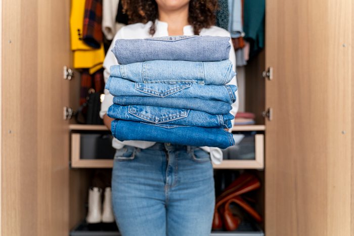 close up of woman holding jeans while cleaning out closet