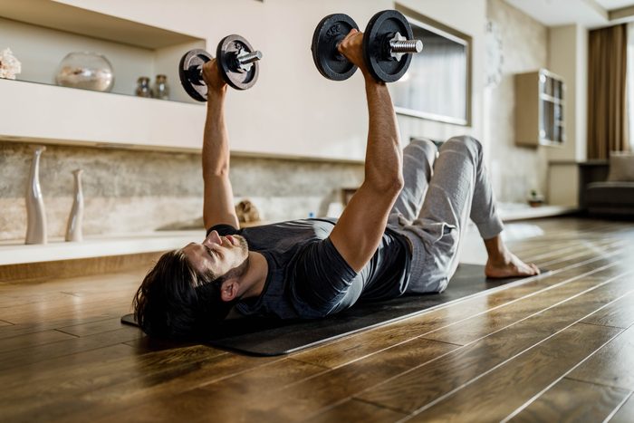 muscular man lifting weights at home