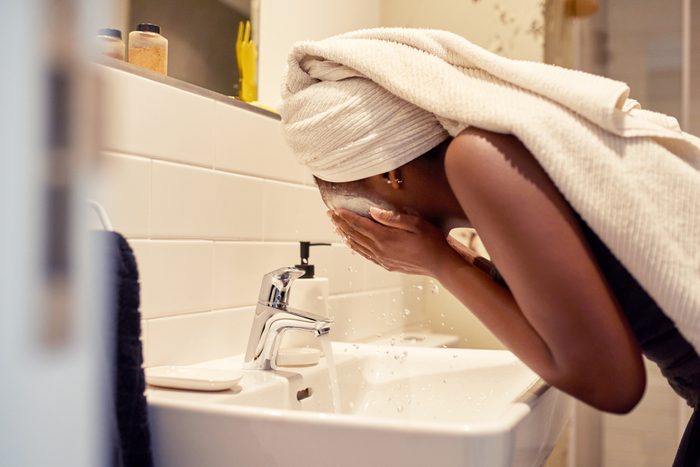 young woman washing face in bathroom at home