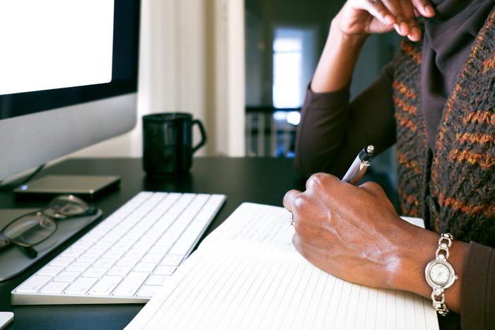 Woman Working From Home Takes Notes at Computer