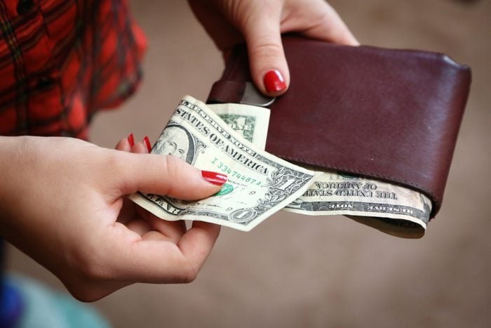 close up of hands, one holding a wallet, the other holding a folded dollar bill for a tip