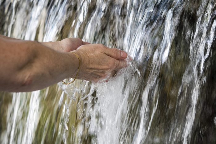 woman's hands in a natural waterfall