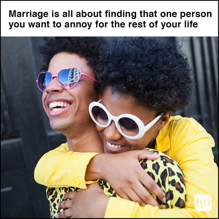 a smiling young African American woman hugging her laughing boyfriend from behind