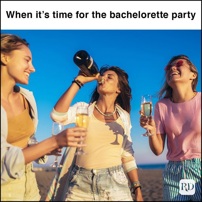 Happy young women drinking champagne at bachelorette party on the beach