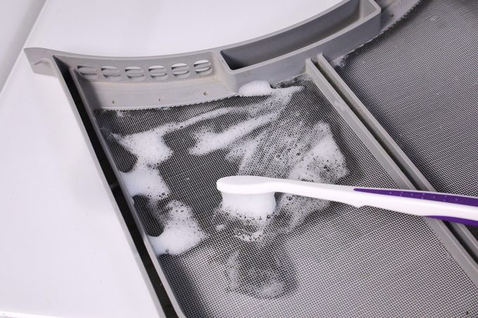 Limpie la trampa de pelusas de una secadora con un cepillo de dientes