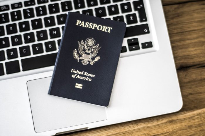 passport on top of laptop on wood desk