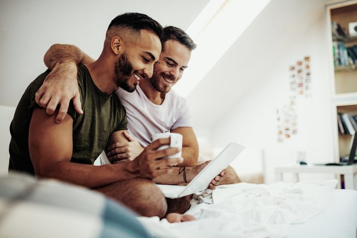 Gay couple at home using laptop to plan future