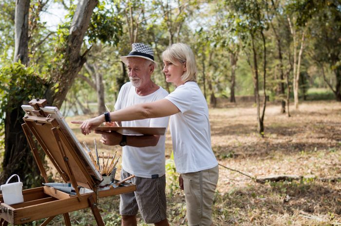 Mature man and woman creating a painting outside in nature