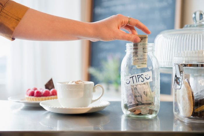 woman putting money into tip jar at cafe
