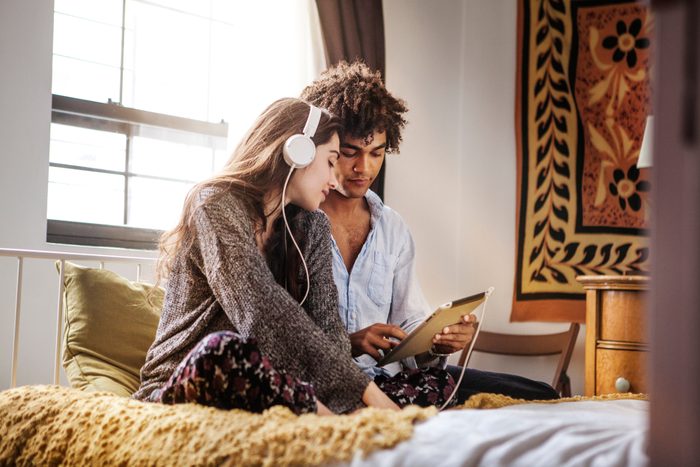 Couple listening to music while sitting on bed at home